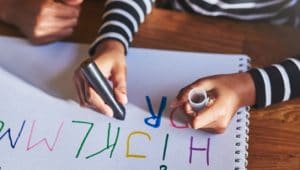 criança desenhando e escrevendo em aula de alfabetização e letramento