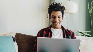 estudante de faculdade no sofá sorrindo para o computador