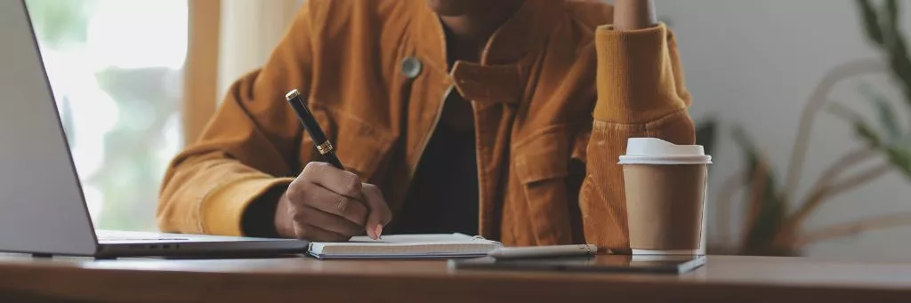 estudante anotando e mexendo em computador