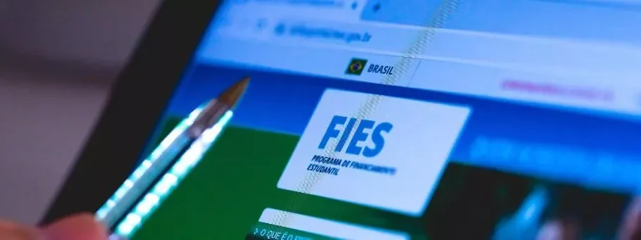 pessoa apontando caneta para tela de computador com site de fies