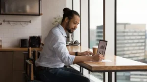 homem fazendo anotações e vendo gráficos em computador